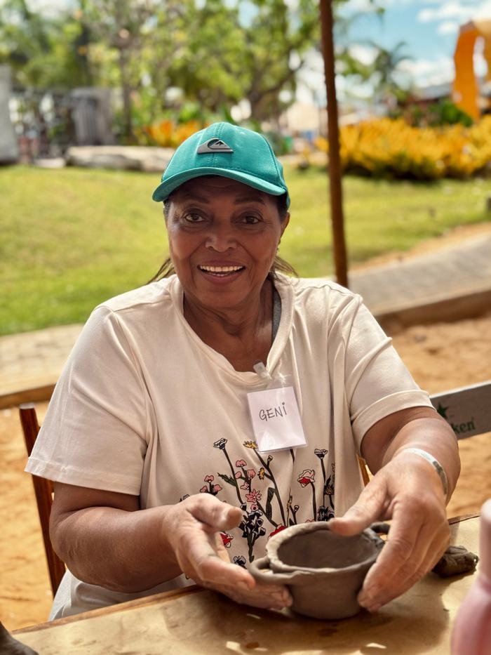 Participante idosa mostrando sua peça de cerâmica