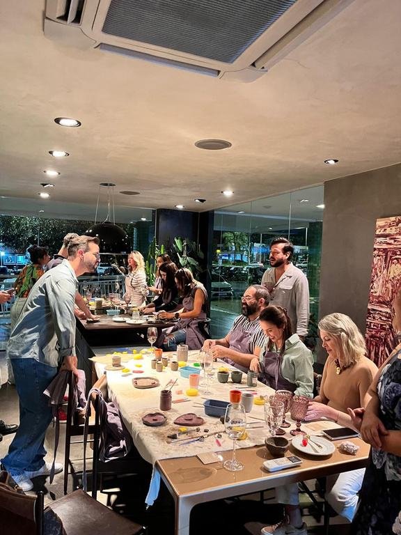 Mesa longa com participantes modelando argila